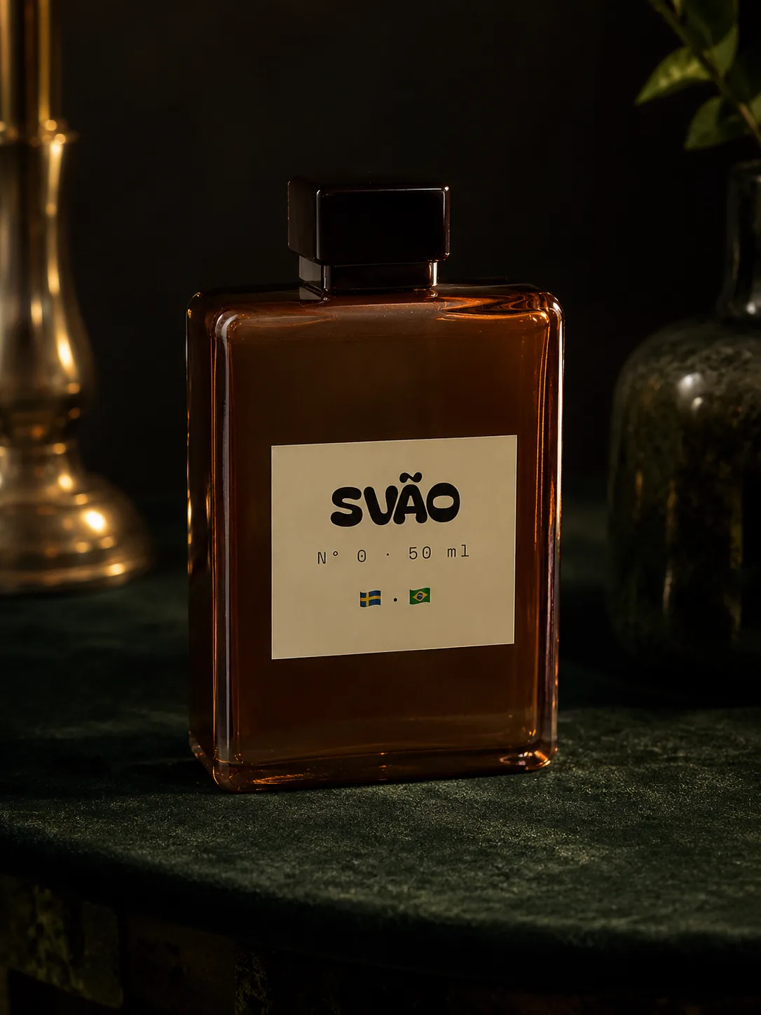 A photograph of SVÃO Nº 0 — a tall amber-glass cologne bottle with a dark cap, its cream label reading SVÃO with a small Swedish and Brazilian flag medallion below, sitting on a deep-green velvet surface in dim, moody lighting.